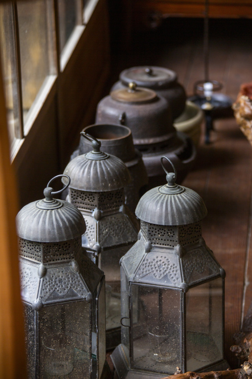 Antique metal lanterns and iron kettles displayed inside a tradi