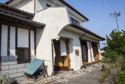 Earthquake-damaged abandoned house with broken walls and debris,
