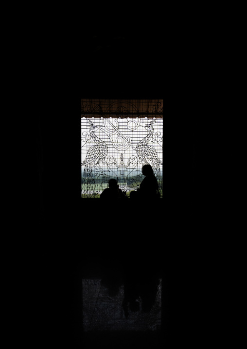 People silhouettes in front of artistic iron work window, Tamil Nadu, Chettinad, India