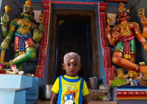 Indian boy in front of deities statues, Tamil Nadu, Karaikudi, India