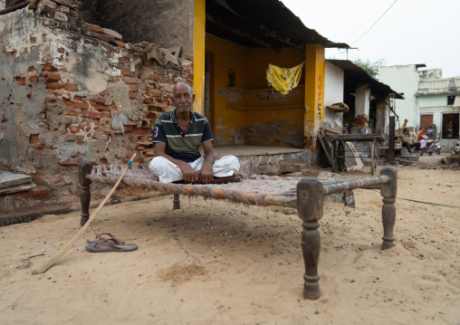 Indian man sit ona traditional bed in the street, Rajasthan, Mukundgarh, India