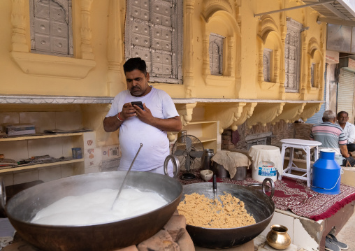 Indian man speaking on the phone while making sweets, Rajasthan, Ramgarh Shekhawati, India