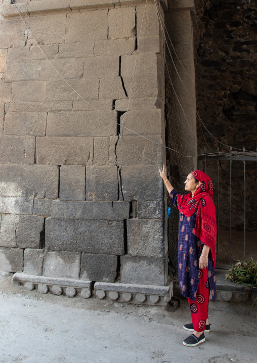 Kashmiri woman below a Mughal arched gate in old city wall, Jammu and Kashmir, Srinagar, India