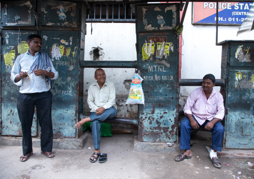 Indian men sit in front of old telecom cabinets in old Delhi, Delhi, New Delhi, India