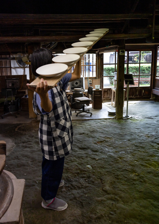 Artisan carrying plates in Genemongama porcelain atelier, Kyushu region, Arita, Japan