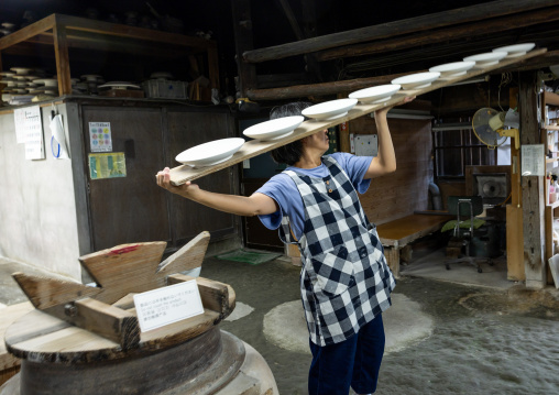 Artisan carrying plates in Genemongama porcelain atelier, Kyushu region, Arita, Japan