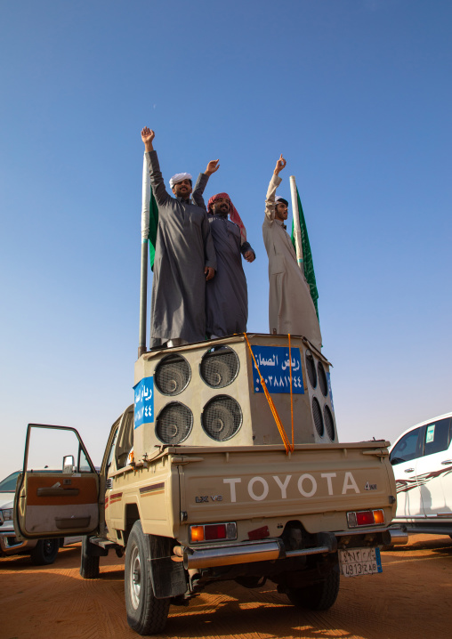 Saudi men dancing on a car during King Abdul Aziz Camel Festival, Riyadh Province, Rimah, Saudi Arabia