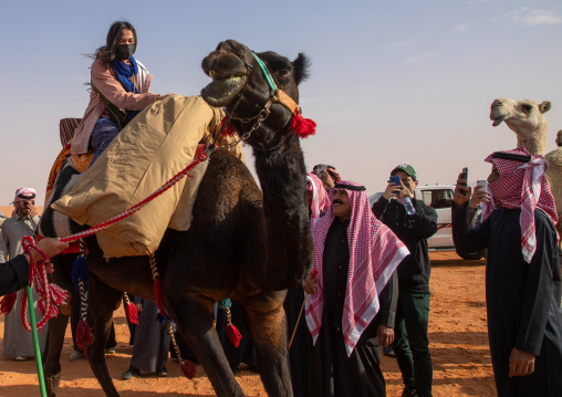 Tourist riding a camel during King Abdul Aziz Camel Festival, Riyadh Province, Rimah, Saudi Arabia