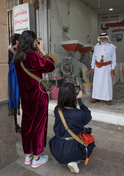 Tourists taking pictures of a saudi man with the traditional janbiya, Najran Province, Najran, Saudi Arabia