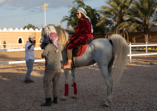 Tourist woman riding an arabian horse in Alhazm stud, Najran Province, Khubash, Saudi Arabia