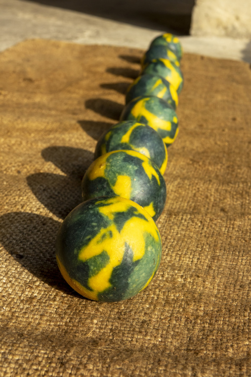 Marbled green and yellow soap balls rest in a row on a burlap cloth in the sunlight, North Governorate, Tripoli, Lebanon