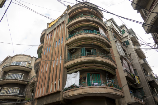 A curved Art Deco apartment building with stacked balconies stands among older neighboring structures, Beirut Governorate, Beirut, Lebanon