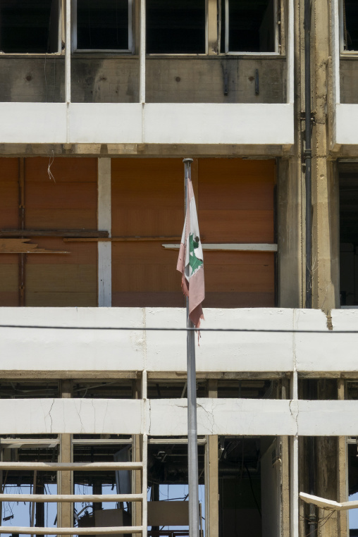 A torn Lebanese flag hangs from a pole in front of the Electricite du Liban headquarters building damaged by the 2020 Beirut port explosion, Beirut Governorate, Beirut, Lebanon