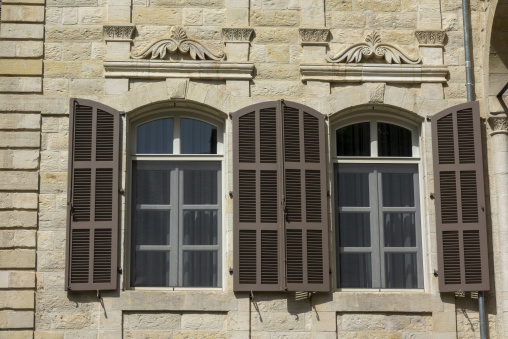 Two arched windows with wooden shutters are set into an ornately carved sandstone facade, Beqaa Governorate, Zahle, Lebanon