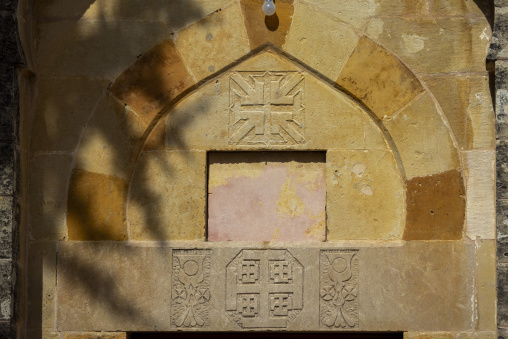 A carved stone archway features a decorative cross and heraldic emblems above an empty marble panel, Mount Lebanon Governorate, Deir el Qamar, Lebanon