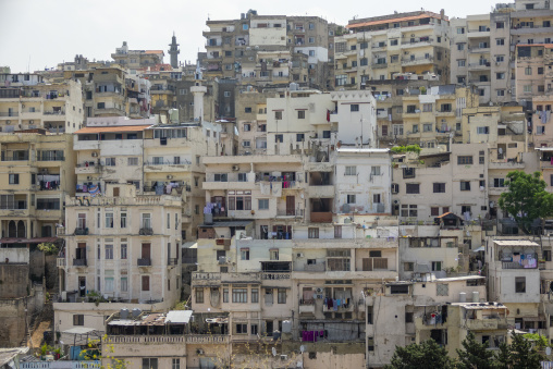 Densely packed apartment buildings climb a hillside beneath a mosque minaret, North Governorate, Tripoli, Lebanon