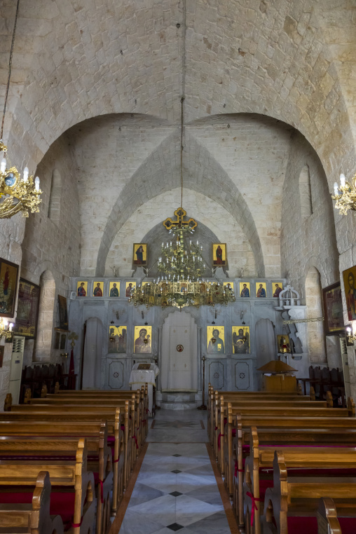 Wooden pews lead toward an ornate iconostasis inside the stone vaulted church of Our Lady of Nourieh Orthodox Monastery, North Governorate, Hamat, Lebanon