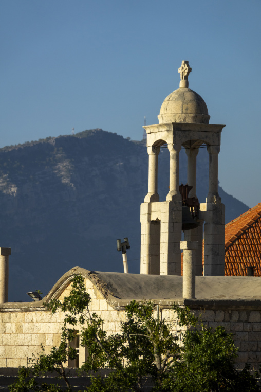 A stone bell tower topped with a cross and dome rises above the red tile roof of Saint Elias Church, Mount Lebanon Governorate, Douma, Lebanon