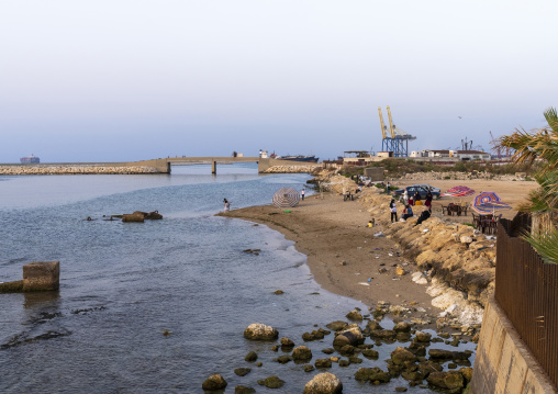 People relaxing on a dirty seafront, North Governorate, Tripoli, Lebanon
