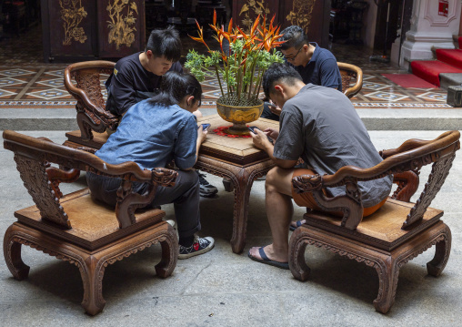 Asian men addicted to their their mobile phones in Pinang Peranakan mansion, Penang island, George Town, Malaysia