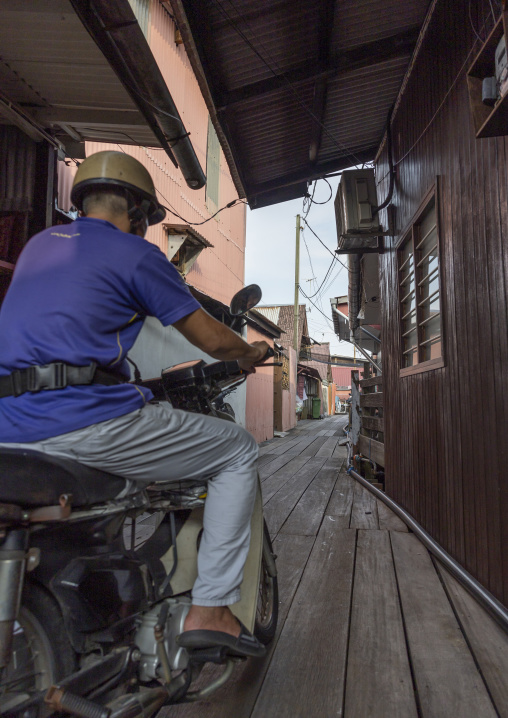 Man riding a motorcycle in Chew Jetty, Penang island, George Town, Malaysia