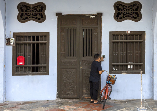 Man with a bicycle entering an heritage house in the old town, Penang island, George Town, Malaysia