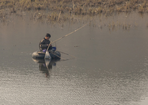 Man fishing on a truck tyre in the countryside, South Pyongan, Nampo, North Korea