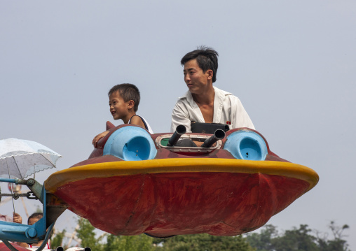 North Korean father and son in a flying saucer attraction in Taesongsan funfair, DGC, Pyongyang, North Korea