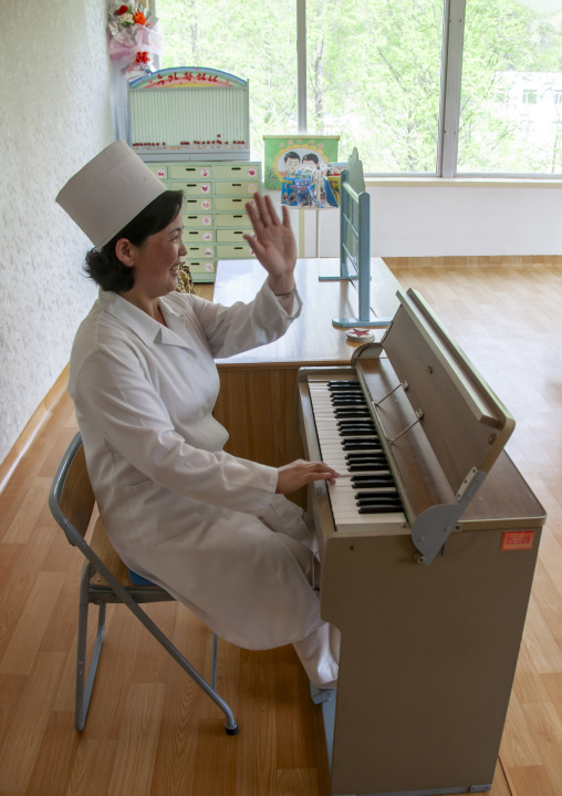 Nurse playing organ in an orphanage, South DGC, Nampo, North Korea