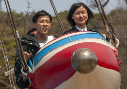 People having fun on a plane attraction in Taesongsan funfair, DGC, Pyongyang, North Korea