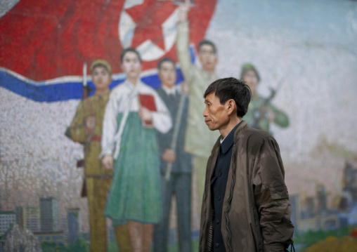 North Korean man in front of a fresco in Puhung metro station, DGC, Pyongyang, North Korea