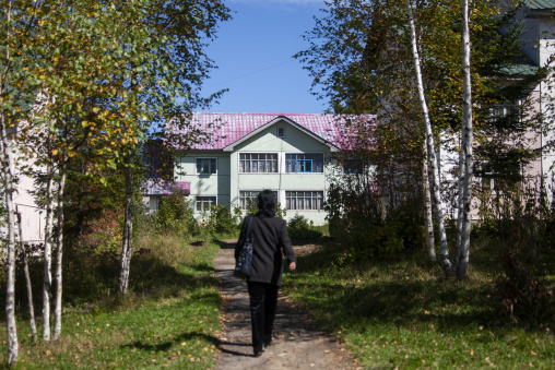 Woman on a path leading to apartment house, Ryanggang, Samjiyon, North Korea