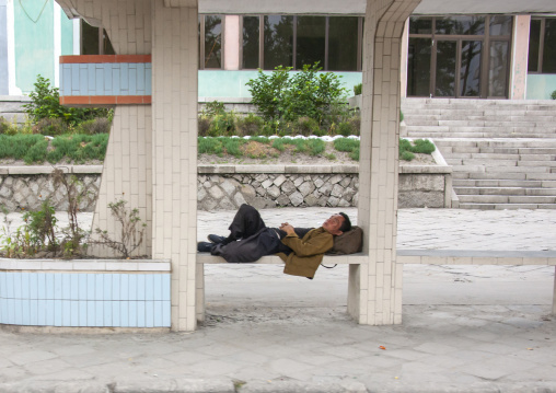 North Korean man sleeping at a bus stop, North Hwanghae, Kaesong, North Korea