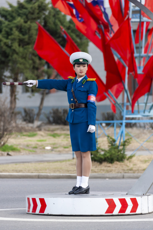 North Korean female traffic security officer in the street in front of red flags, DGC, Pyongyang, North Korea