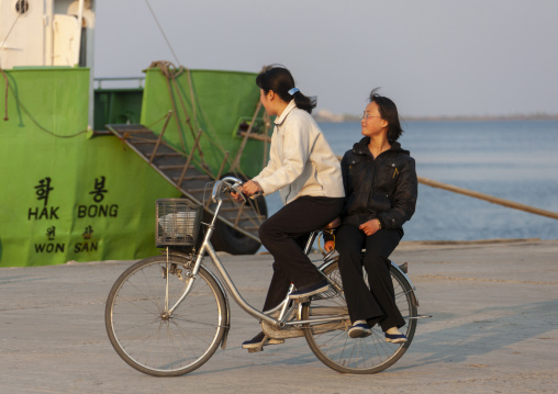 North Korean women riding a bicycle, Kangwon Province, Wonsan, North Korea