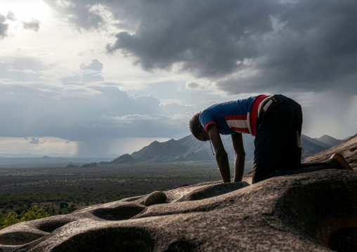 Lotuko tribe woman grinding grains in a hole in the rock, Central Equatoria, Illeu, South Sudan
