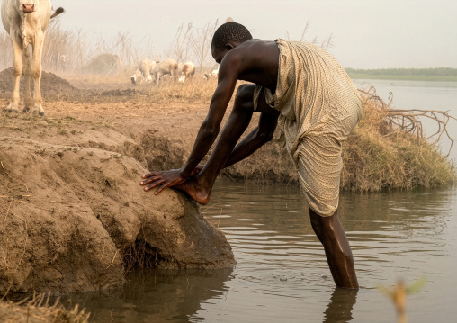 Mundari tribe man washing his feet in river Nile, Central Equatoria, Terekeka, South Sudan