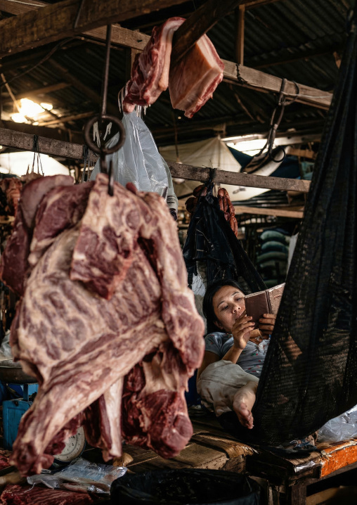 Woman reading and selling meat in a market, Phnom Penh province, Phnom Penh, Cambodia