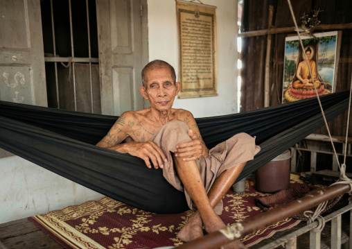 Tatooed monk on a hammock in a monastery, Battambang province, Battambang, Cambodia