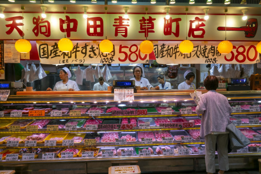 Woman shopping for meat at a butcher stall in Omicho Market, Ish