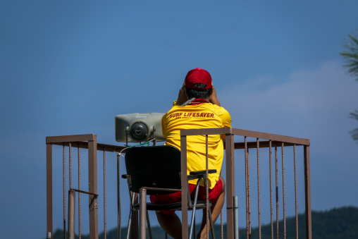 Lifeguard sitting on a wooden watchtower overlooking the beach,