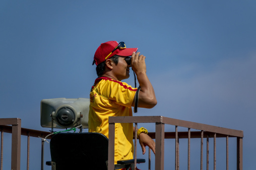 Lifeguard using binoculars to watch over swimmers at the beach,