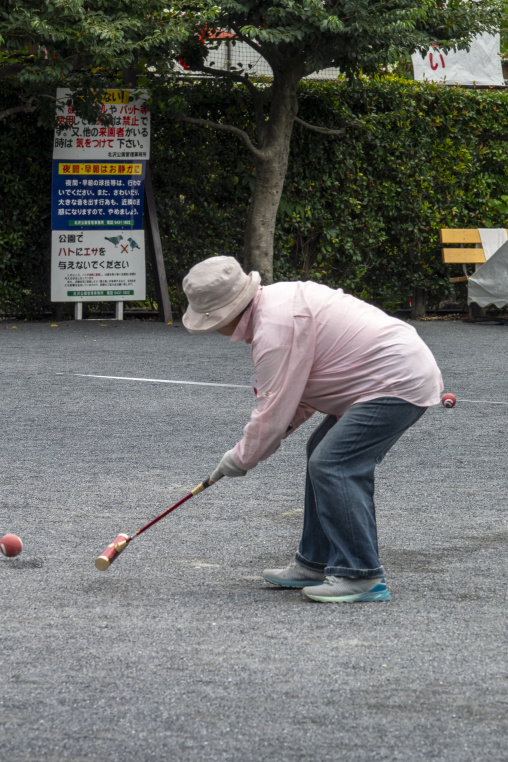 Elderly woman hitting a ball with a mallet during a gateball gam