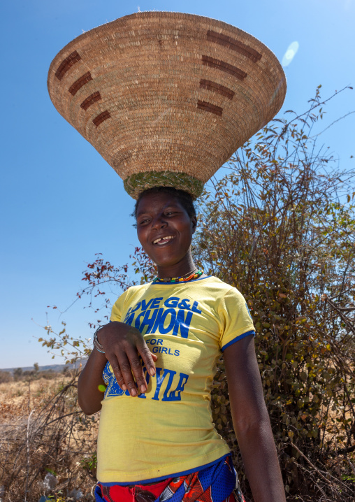 Mumuhuila woman wearing a western shirt and carrying a basket on her head, Huila Province, Chibia, Angola