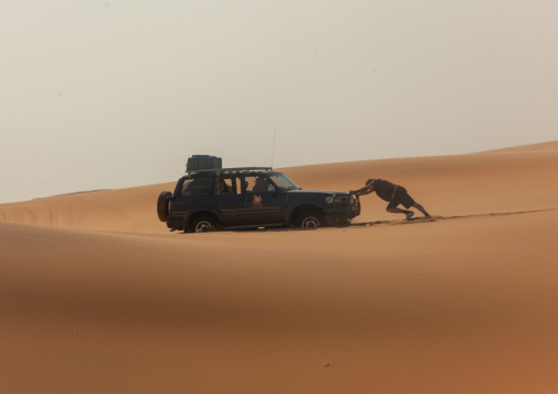 Man pushing a broken down car in the namib desert, Namibe Province, Iona National Park, Angola