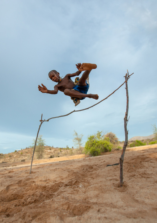 Mucubal tribe boy doing high jumping in the bush, Namibe Province, Virei, Angola