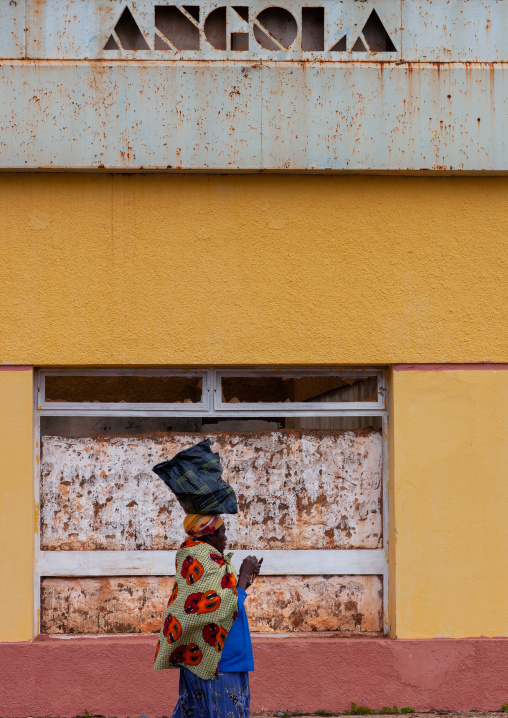 Angolan woman passing in front of a closed bank, Huambo Province, Vila Nova, Angola