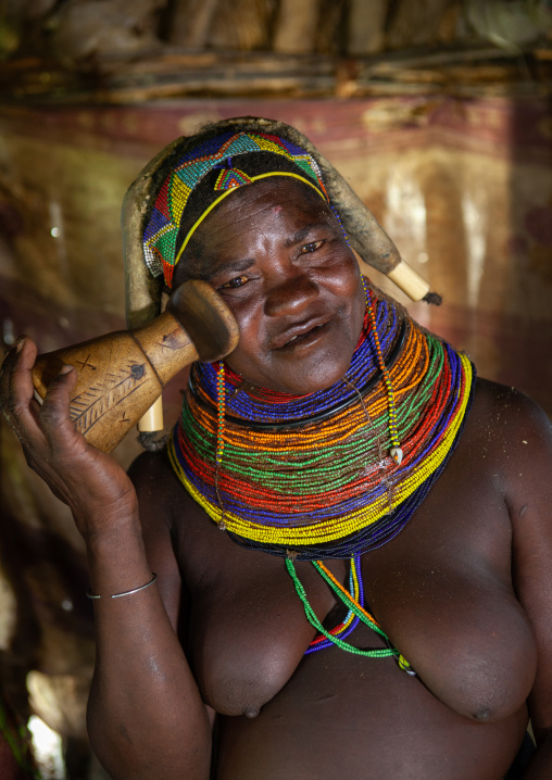 Mumuhuila tribe woman showing how to use a wooden  headrest, Huila Province, Chibia, Angola