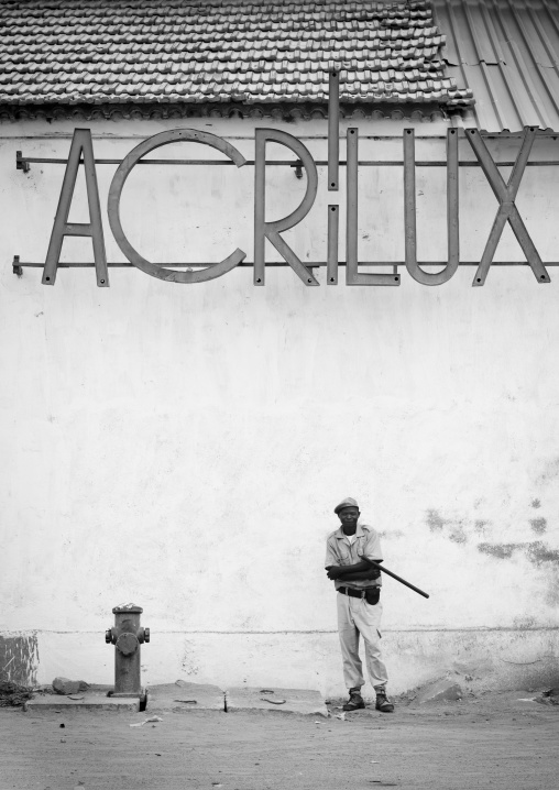 Policeman In Front Of An Old Acrilux Store, Benguela, Angola