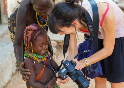 European tourist showing her camera screen to a mumuhuila tribe girl, Huila Province, Chibia, Angola